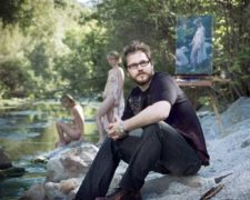 A Photograph of artist Jeremy Lipking with a painting and nude models in background.